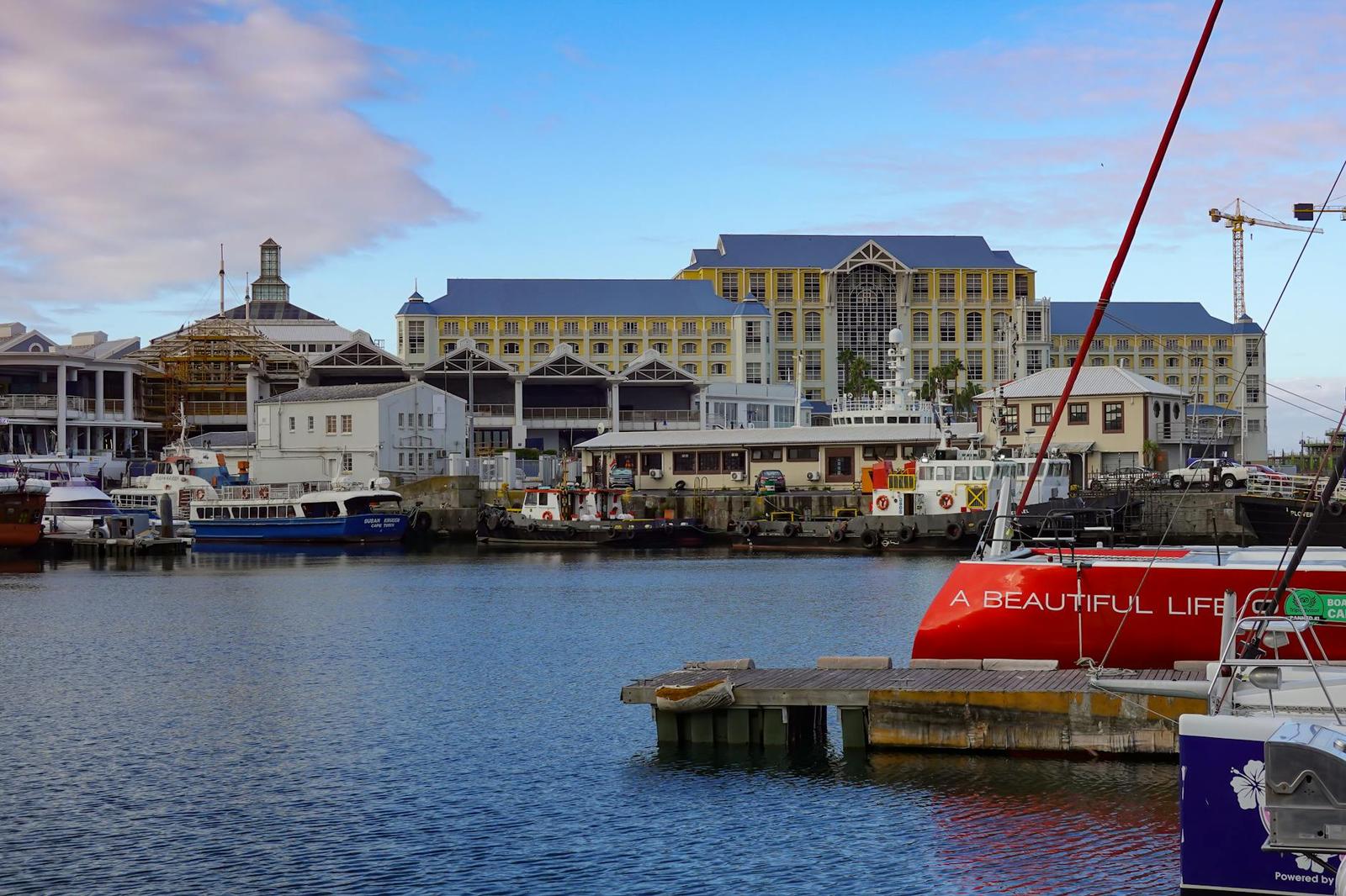 Boats moored at a harbour promenade lined with warehouse-style buildings