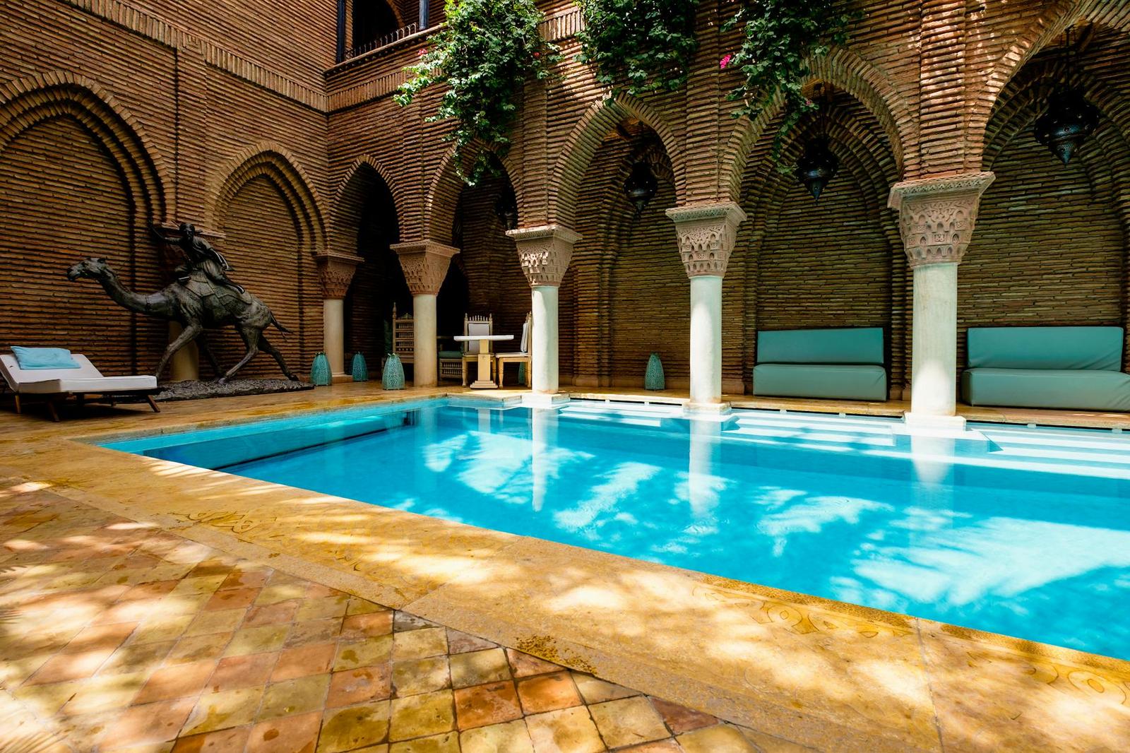 A courtyard pool framed by horseshoe arches and carved columns