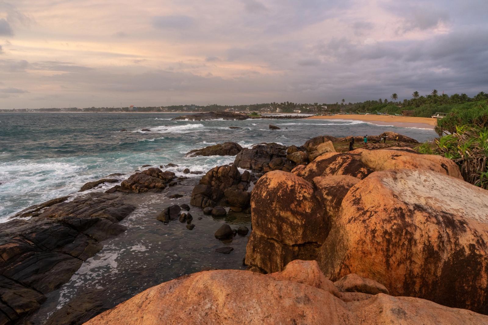 Beautiful view of a Sri Lankan beach at sunset with dramatic rock formations and ocean waves