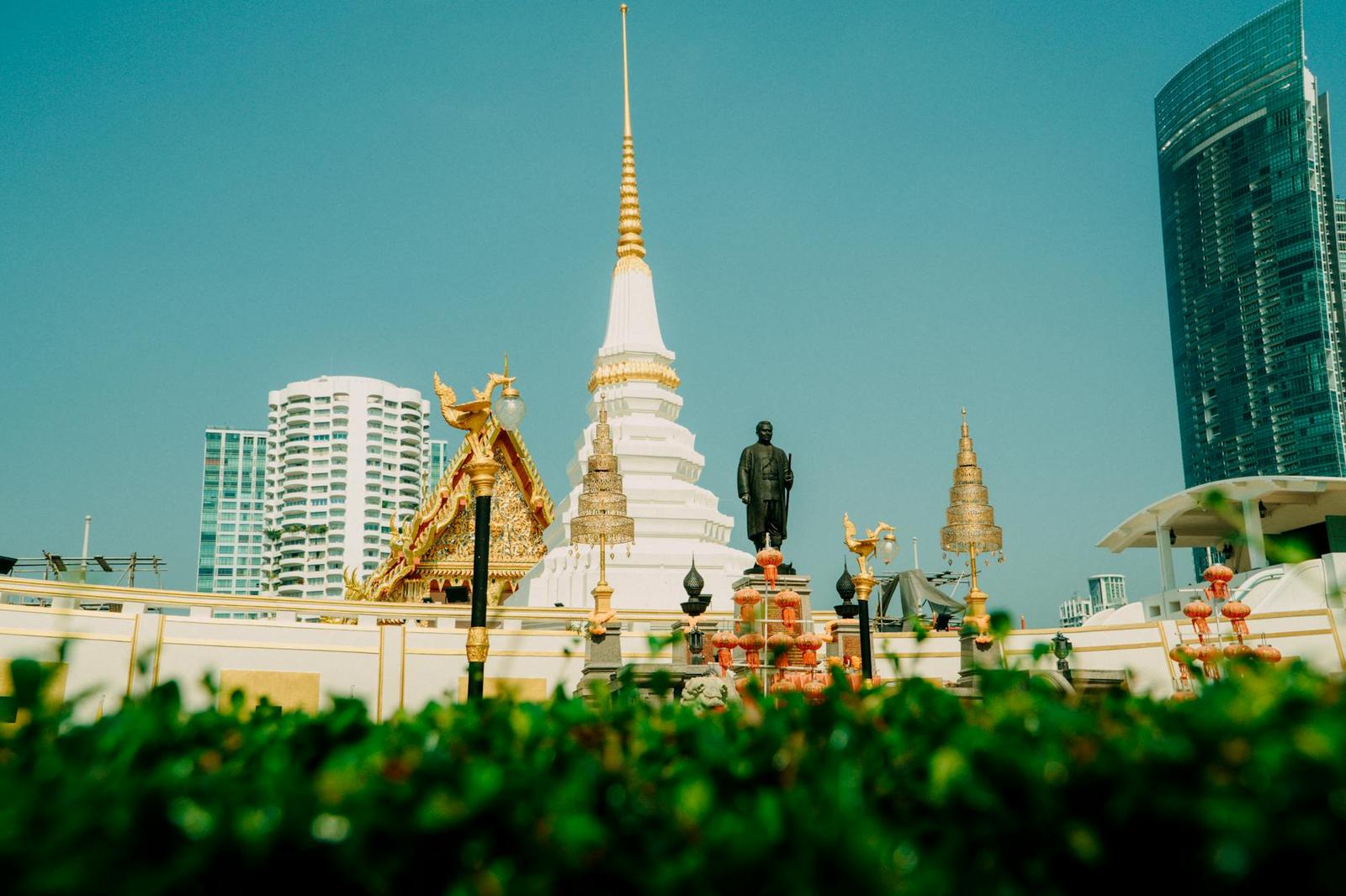 Buddhist temple with golden architecture against a modern city skyline under clear sky