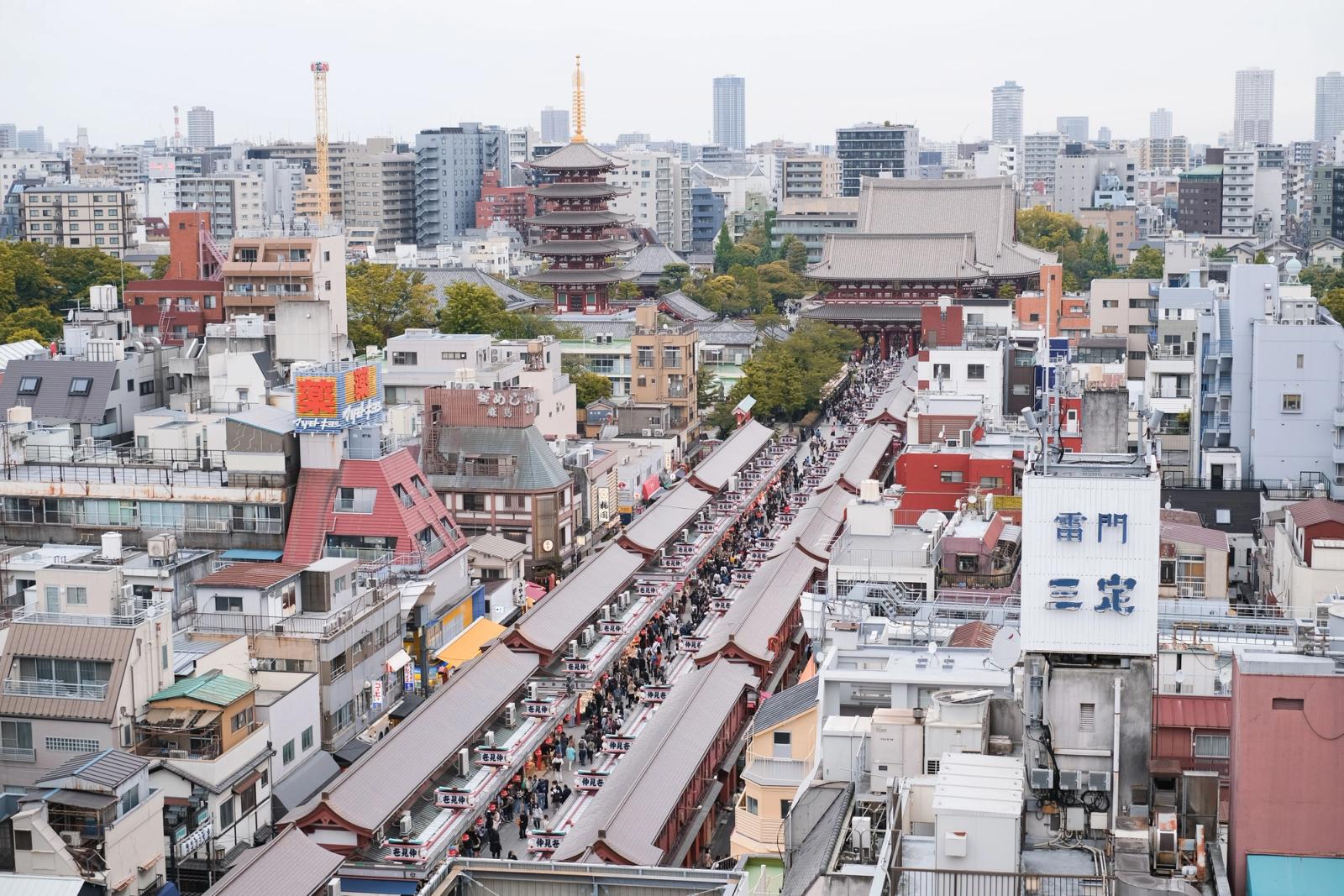 Bustling street scene leading to the historic Senso-ji Temple surrounded by a cityscape in Tokyo