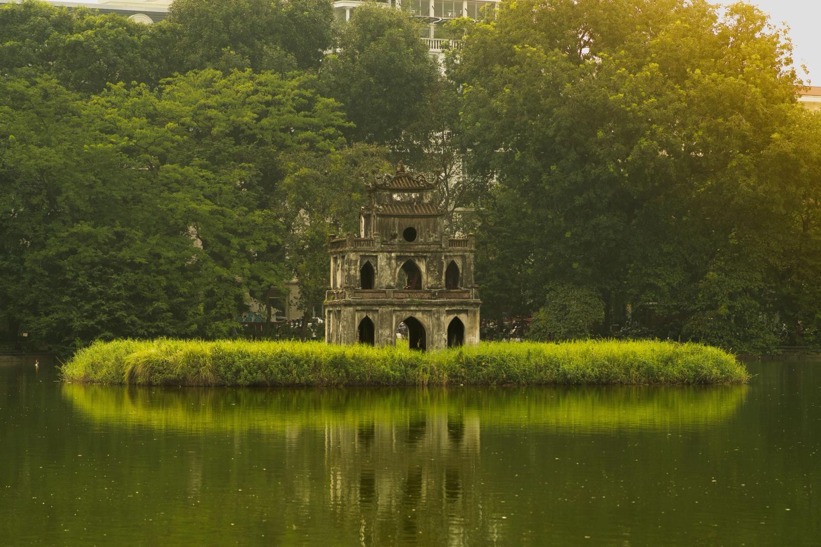 Serene view of Turtle Tower in Hanoi's Hoan Kiem Lake surrounded by lush greenery