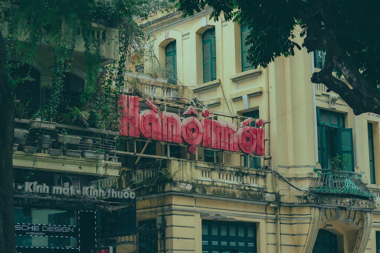 Vintage neon shop sign mounted on a colonial-era building facade