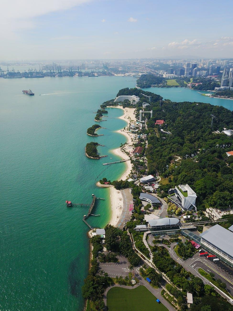 Aerial view of a curving sandy coastline lined with resort greenery