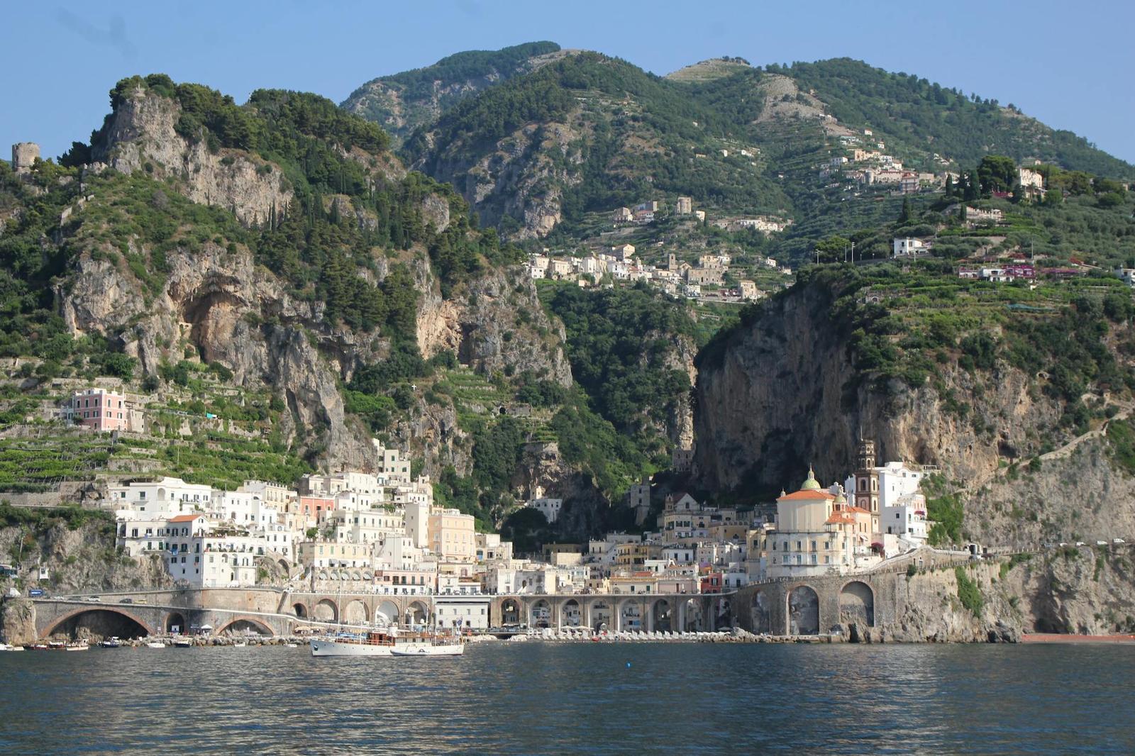 A coastal town nestled between steep cliffs beside turquoise water