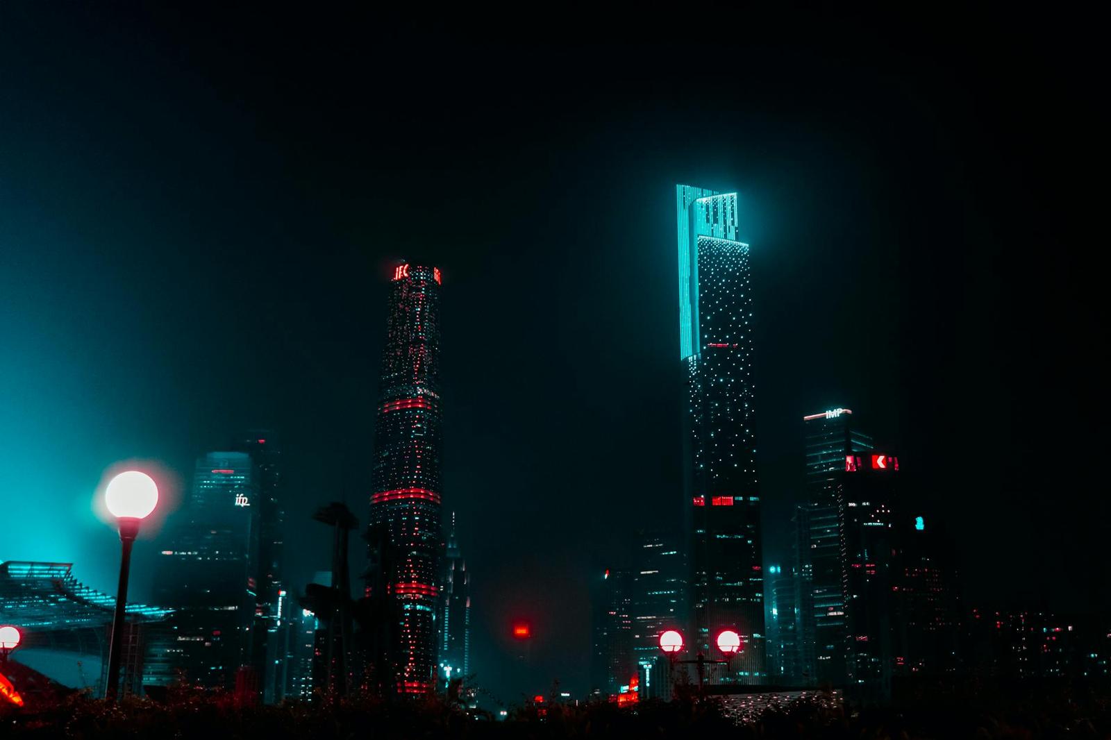 Illuminated skyscrapers glowing teal and red against a night sky