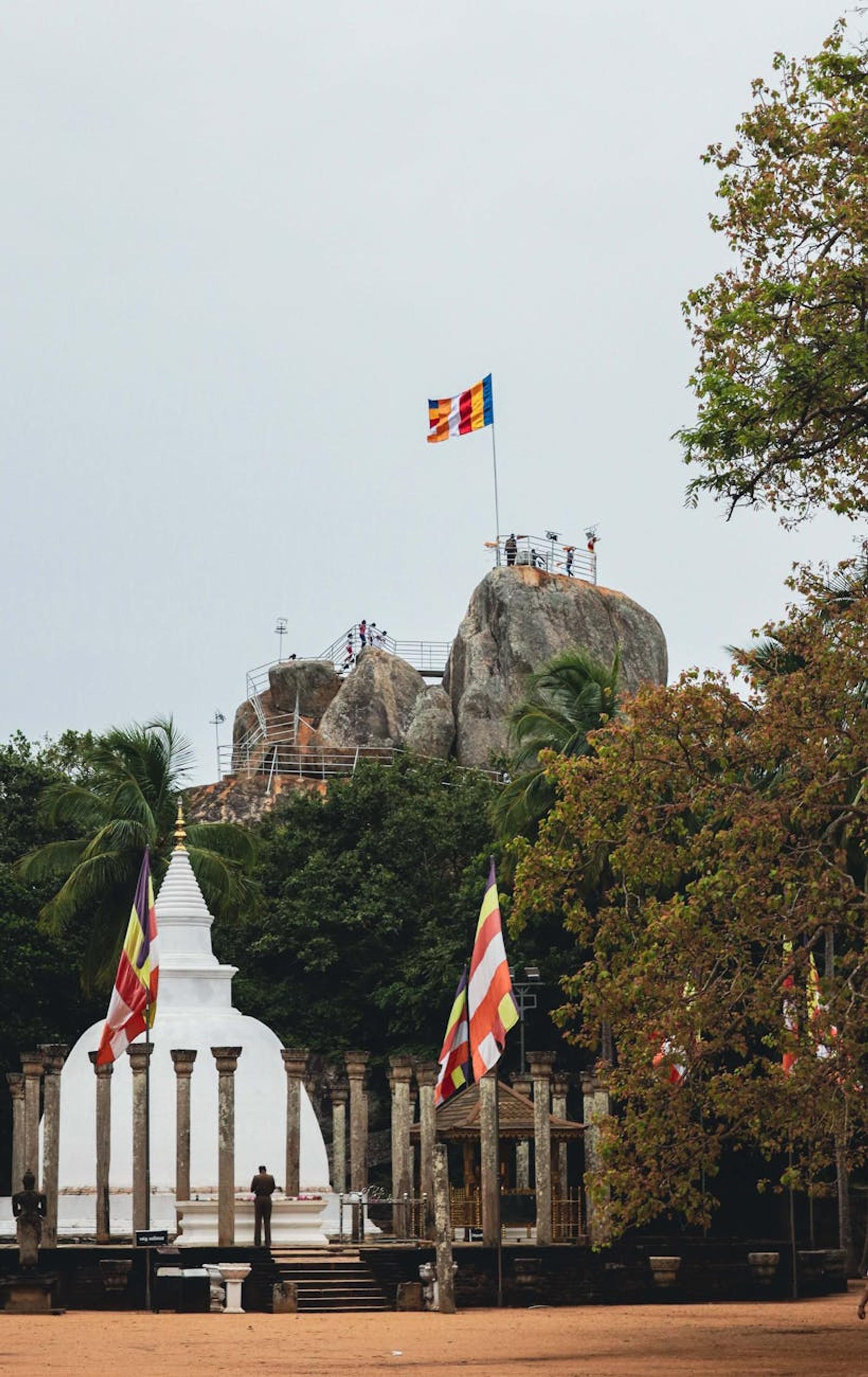 Scenic view of Mihintale Stupa and rock formations with Buddhist flags in Sri Lanka