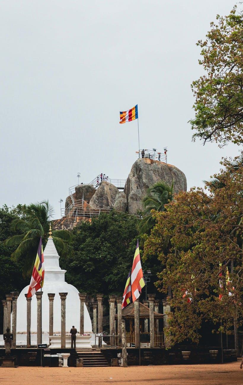 Scenic view of Mihintale Stupa and rock formations with Buddhist flags in Sri Lanka