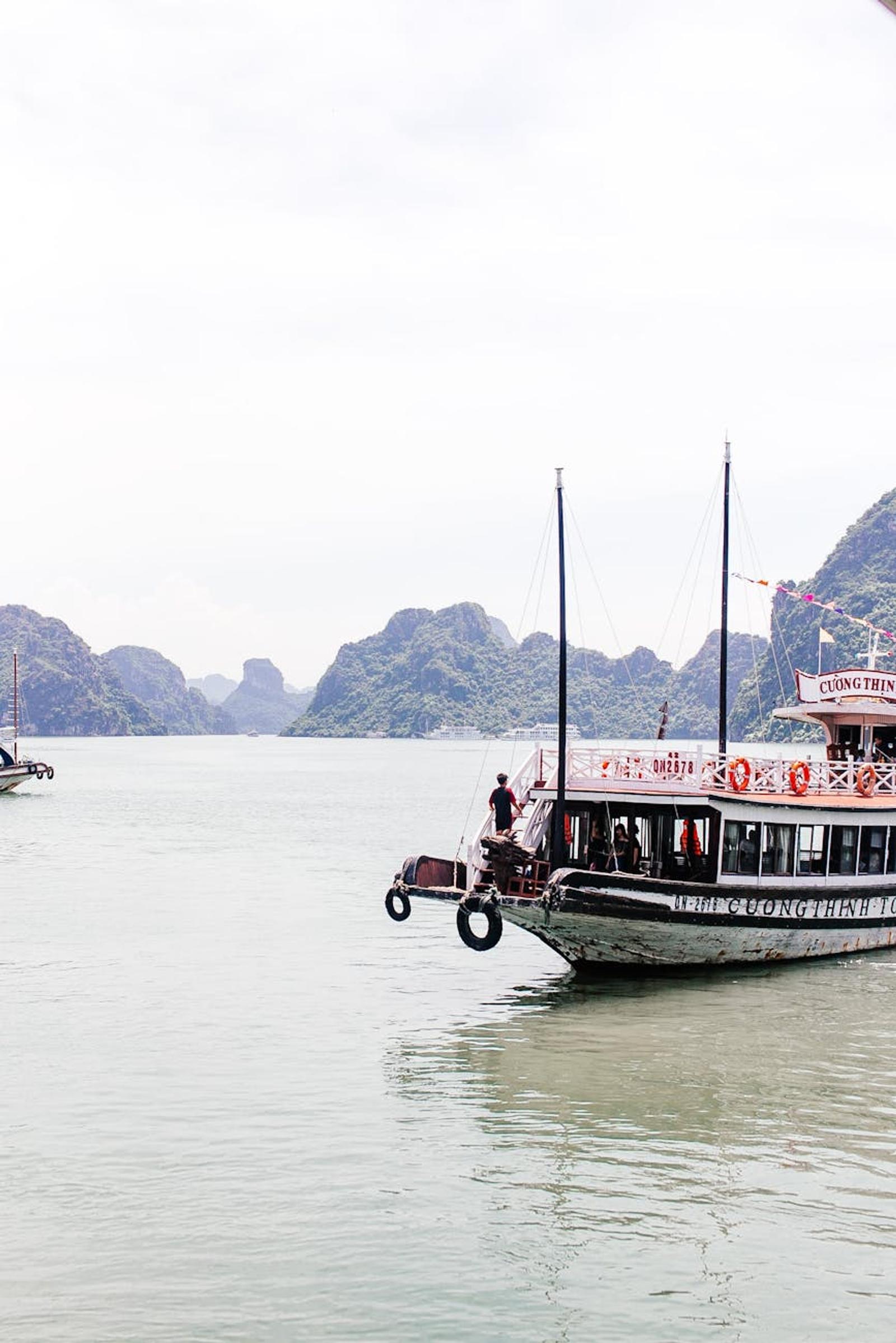 Wooden cruise boat anchored with limestone islets in the background