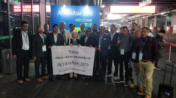 A group of people standing together in front of a large banner.