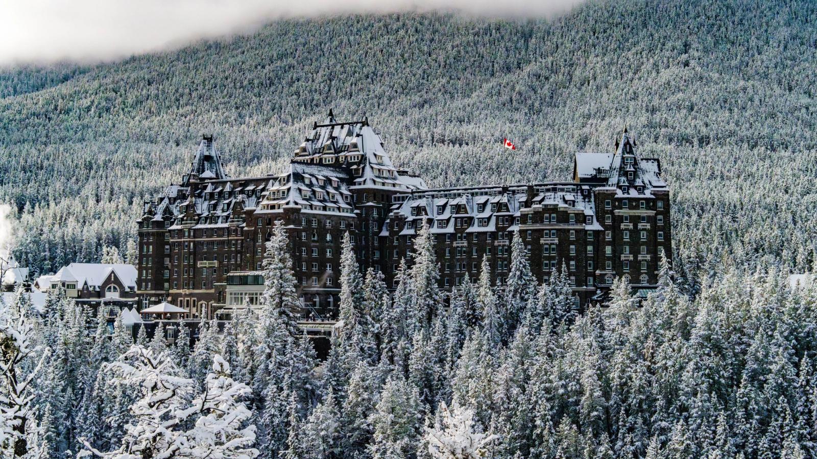 Stunning winter view of Banff Springs Hotel surrounded by snowy forests and mountains in Canada