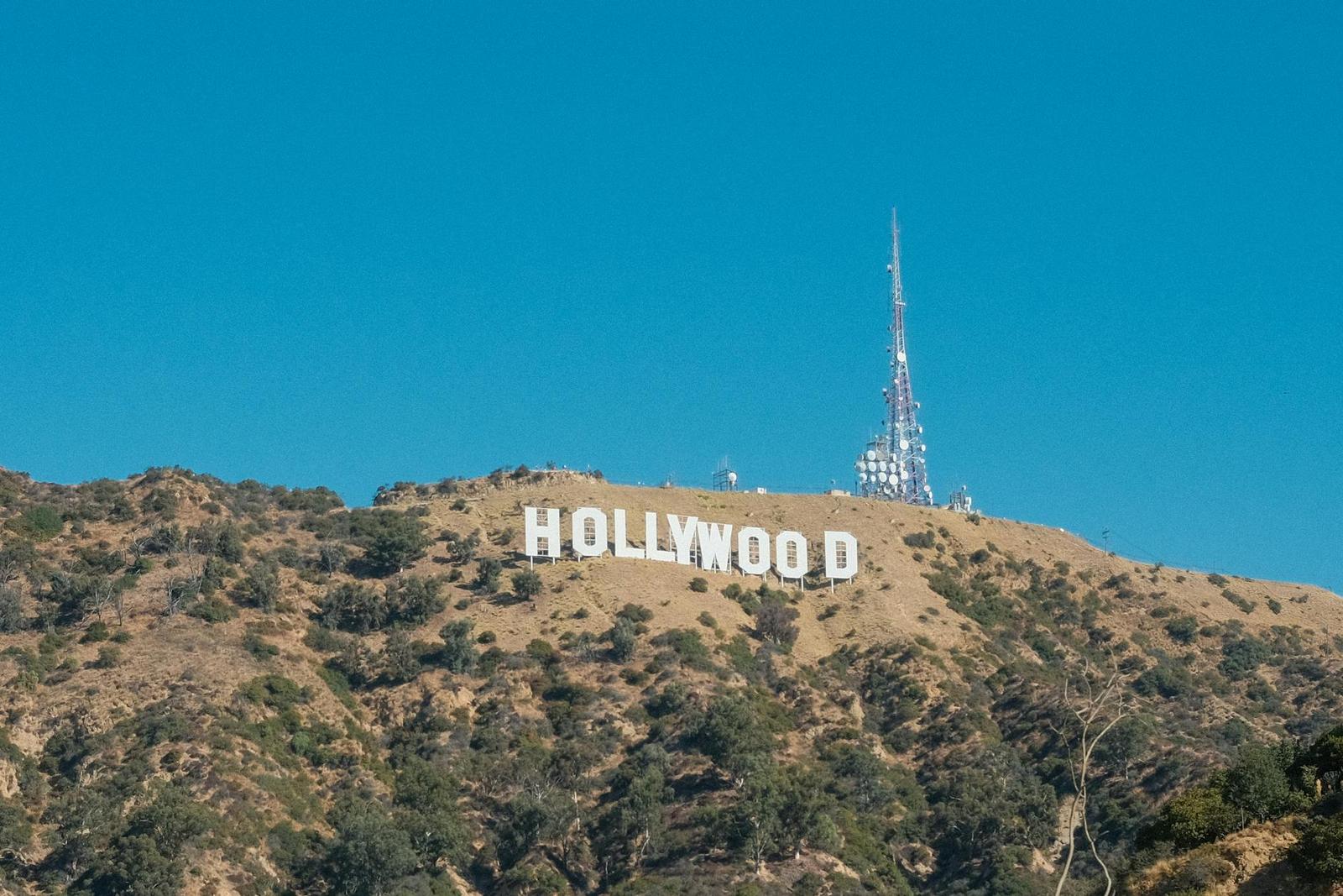 The Hollywood sign on a dry hillside beneath a radio tower and clear sky