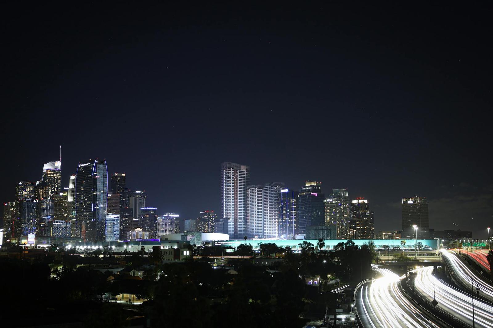 A downtown skyline lit at night with light-trail traffic streaming below