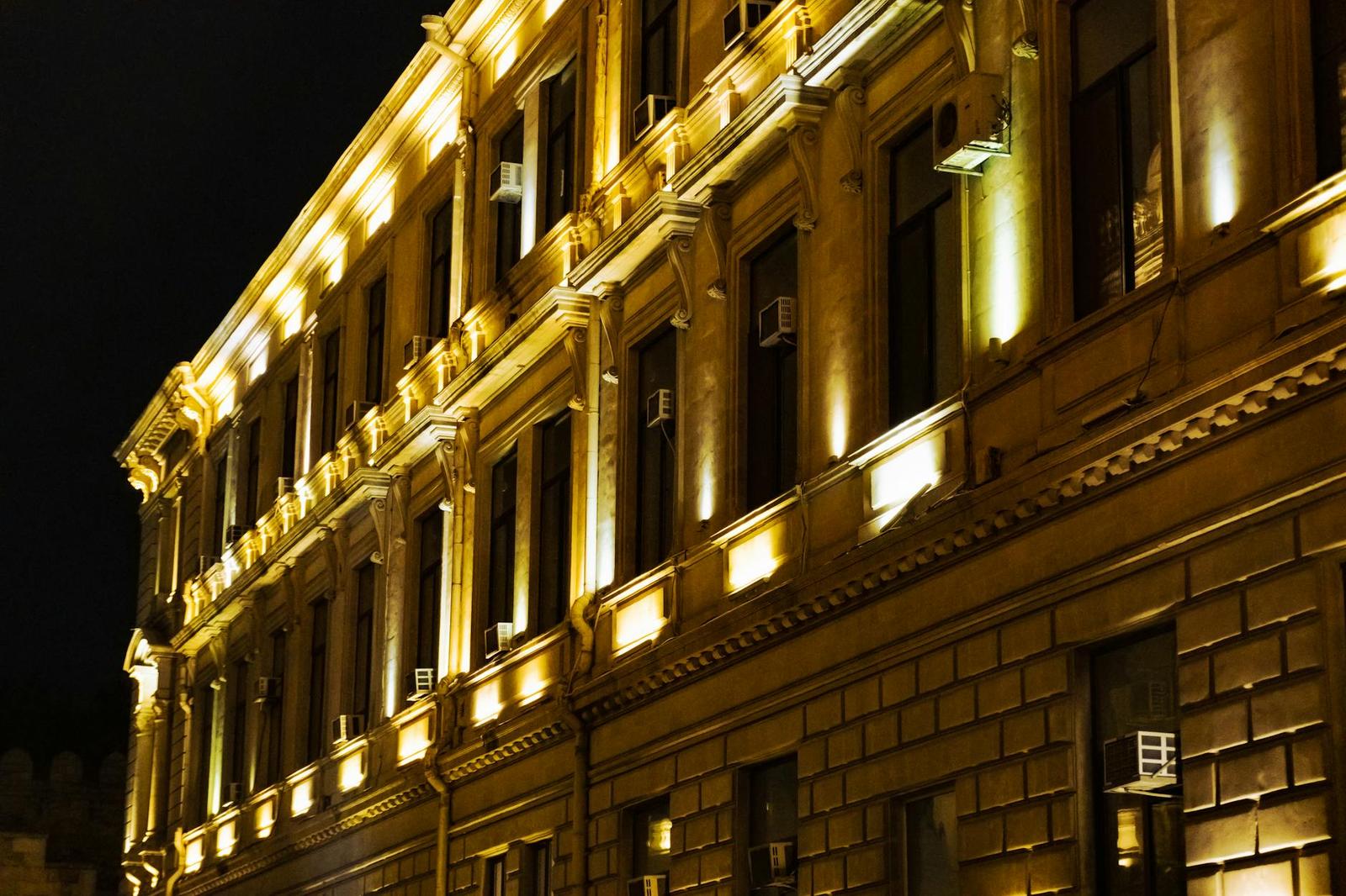 An ornate stone building facade illuminated gold by uplighting at night