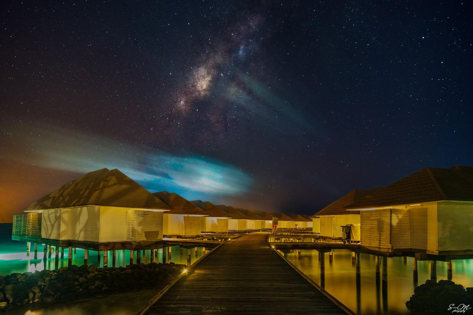 A row of overwater bungalows beneath a starlit sky