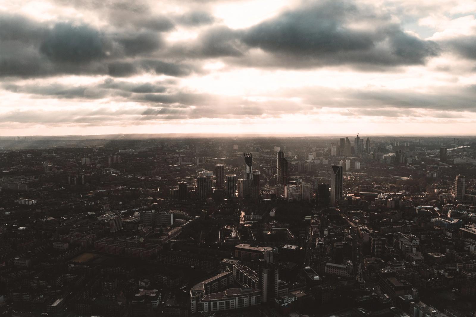 A dramatic aerial view of London cityscape under clouded sky, highlighting urban architecture