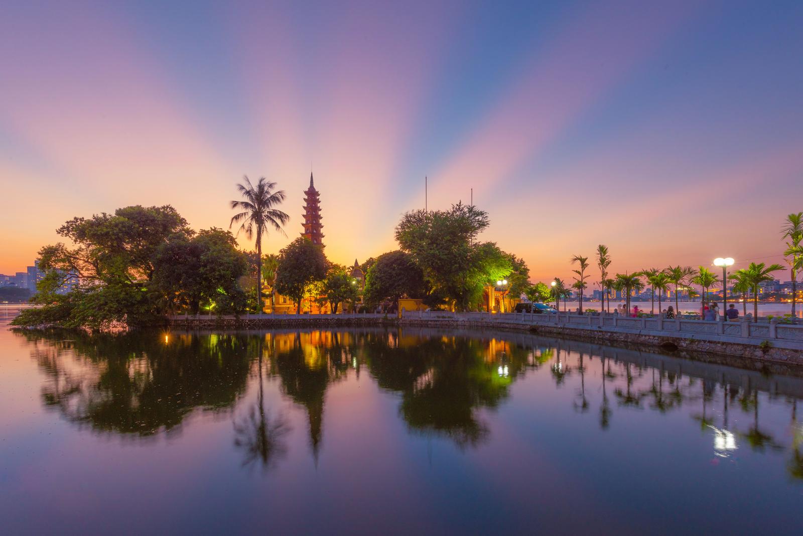A breathtaking view of Tran Quoc Pagoda reflecting over Truc Bach Lake at sunset in Hanoi, Vietnam