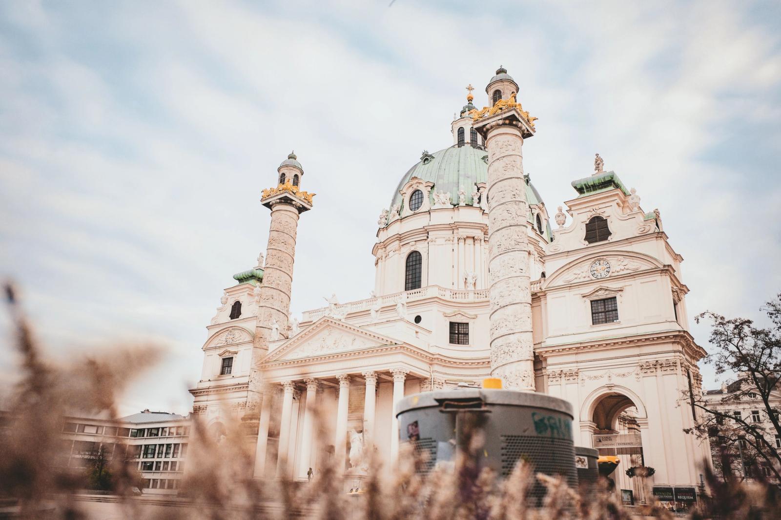 A baroque church facade with twin columns and a green dome