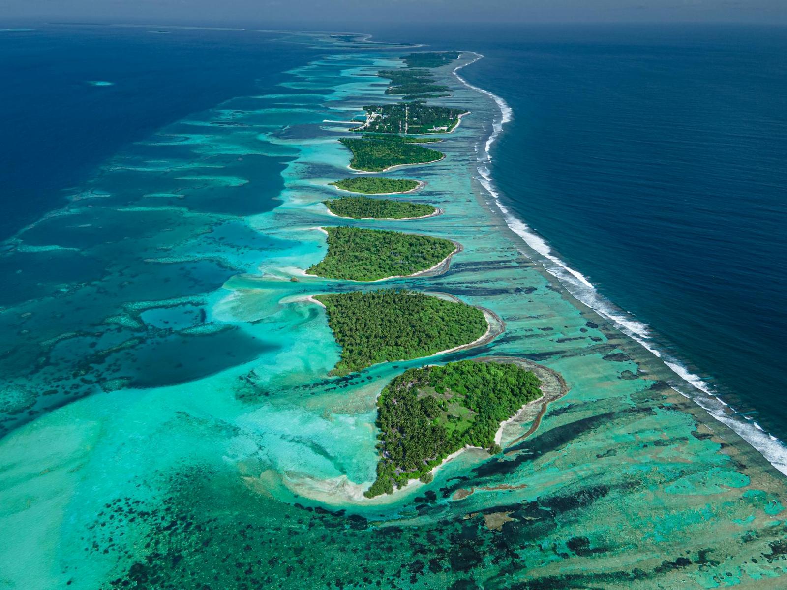 Aerial view of a chain of forested islands strung along a reef