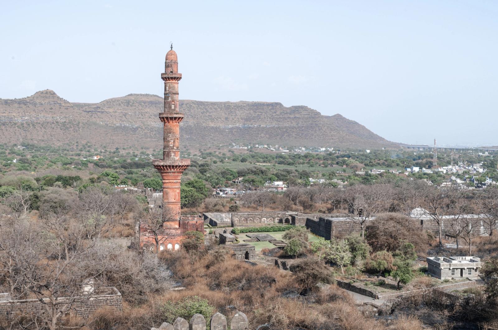 Explore the historic Chand Minar in Daulatabad, India, surrounded by lush hills and ancient architecture