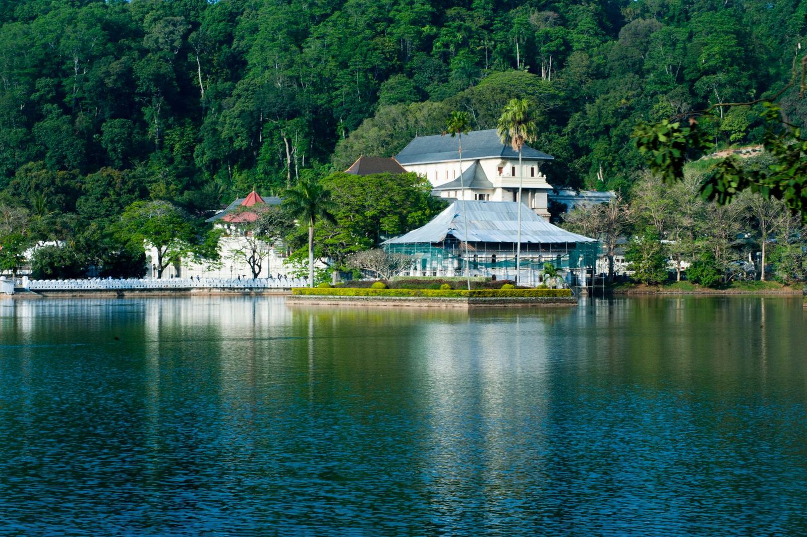 Serene view of Kandy Lake and Temple of the Tooth surrounded by lush greenery in Kandy, Sri Lanka
