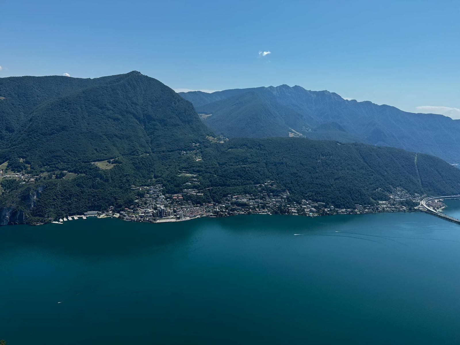 Aerial view of a lakeside town nestled between forested mountain slopes