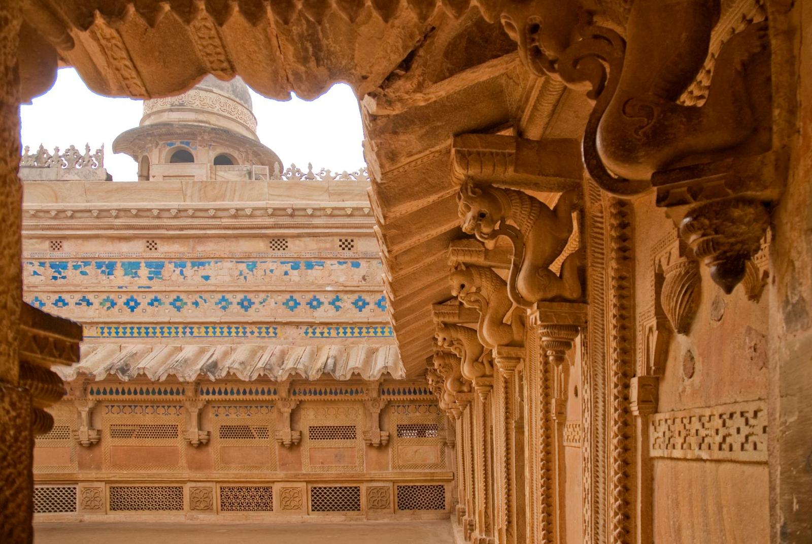 Ornately carved sandstone archway with tiled dome visible beyond
