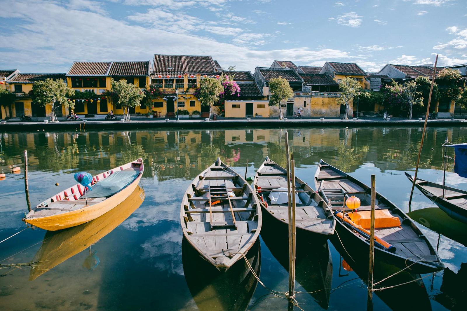 Wooden rowboats moored along a canal beside yellow old town houses