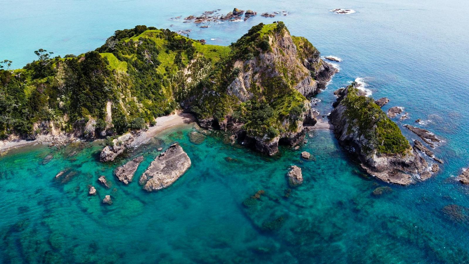 Aerial view of a rocky headland and a hidden cove in turquoise water