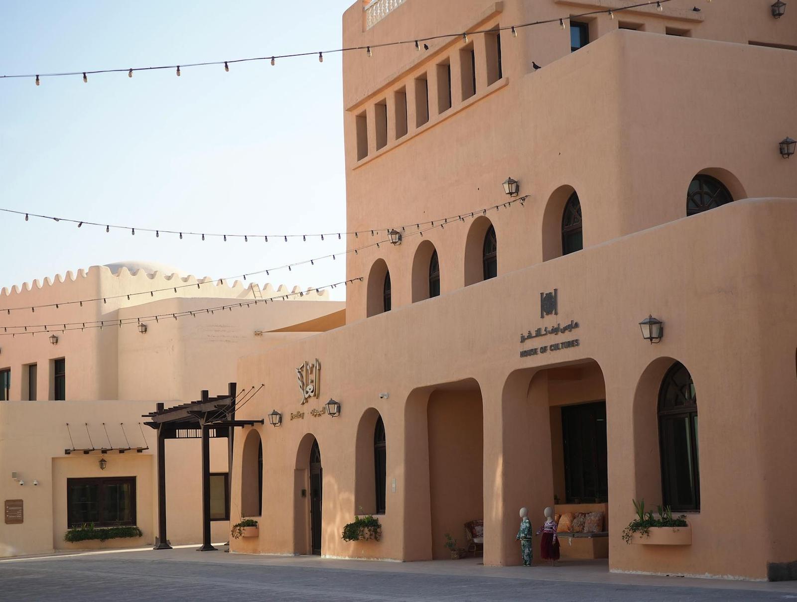 Sandstone building with arched windows and hanging string lights