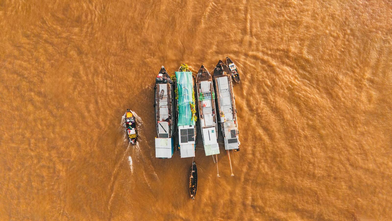 Overhead view of cargo boats clustered on a muddy river