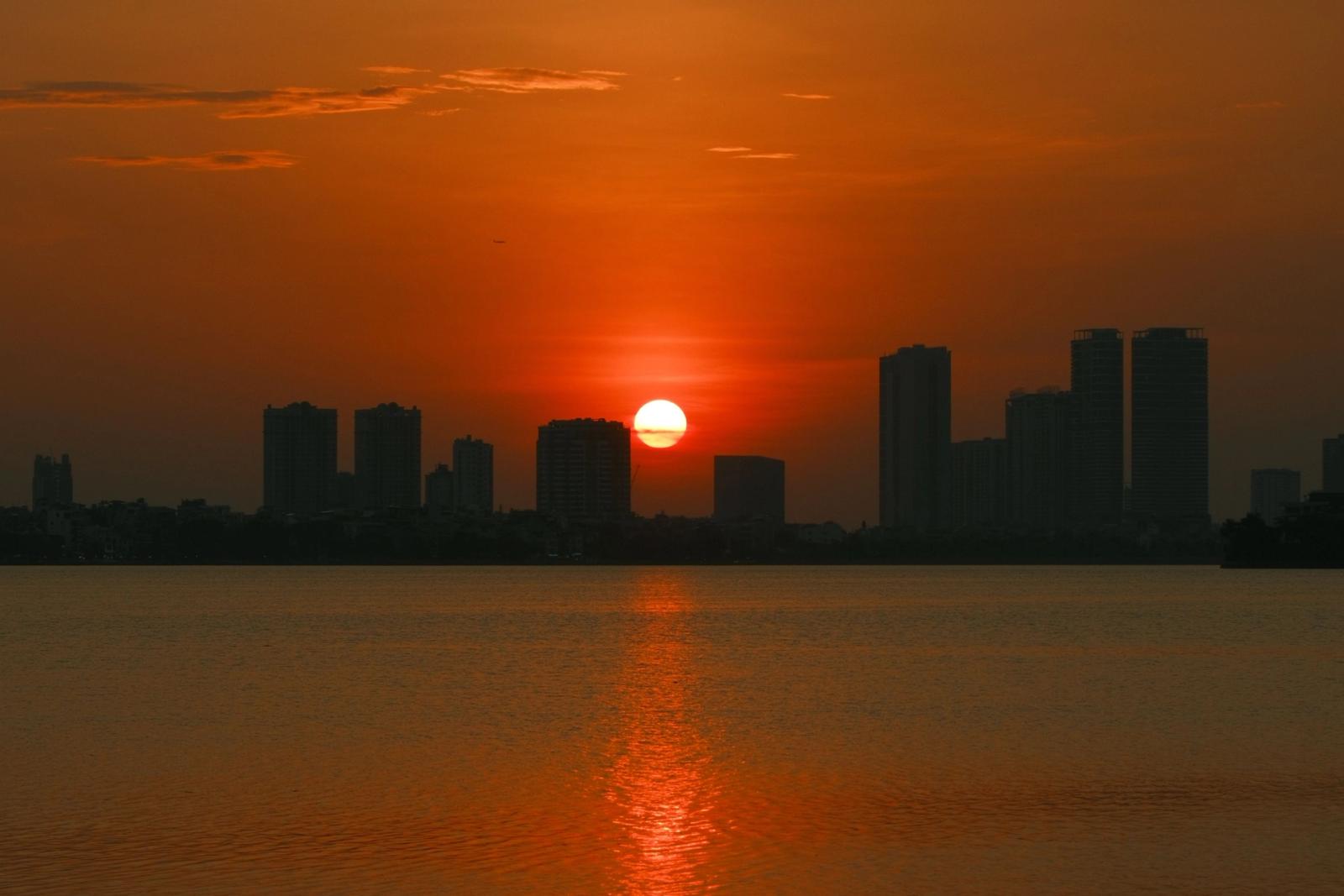 Stunning sunset over Hanoi skyline with a vivid orange sky reflecting on the water