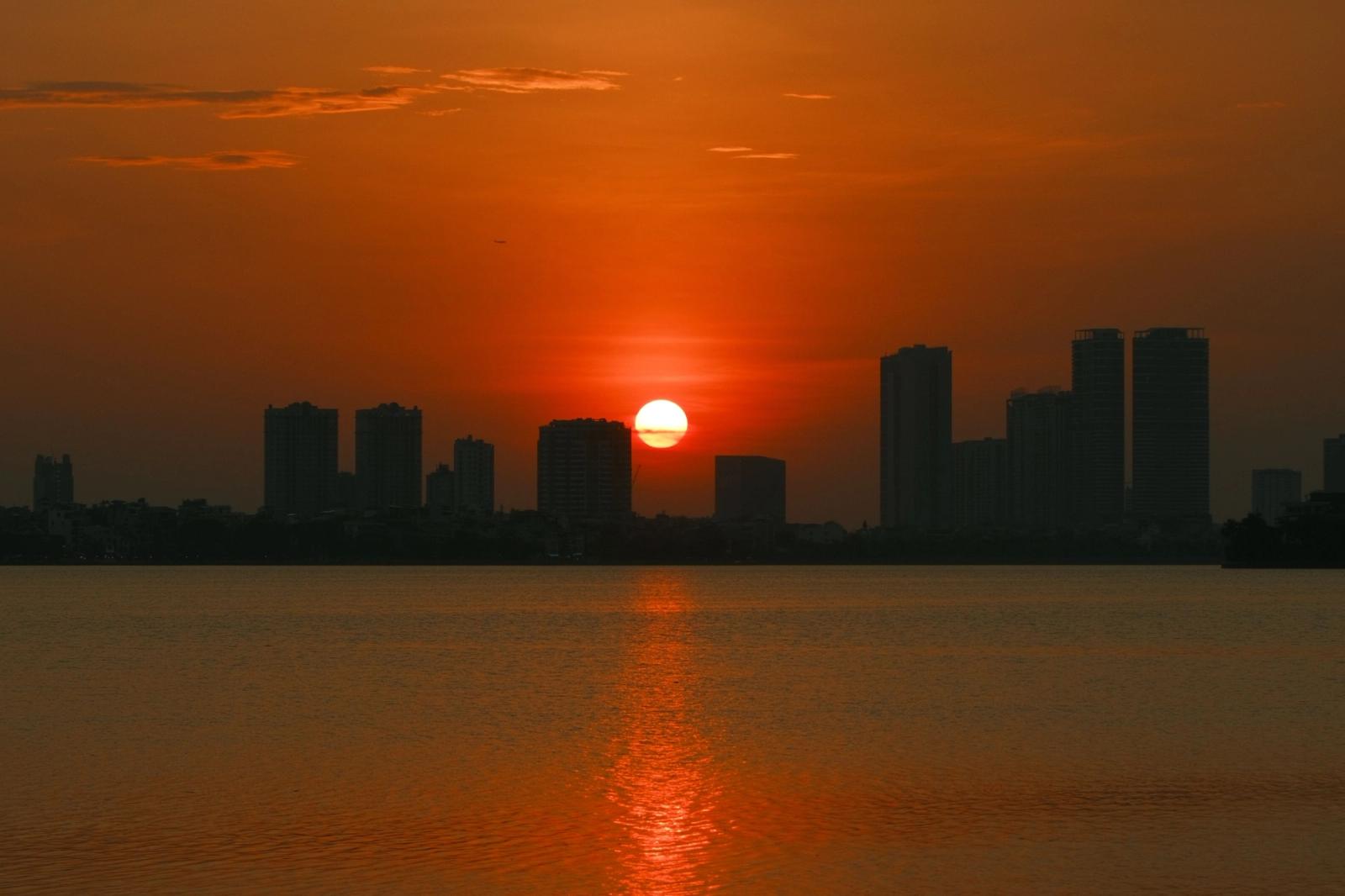 Stunning sunset over Hanoi skyline with a vivid orange sky reflecting on the water