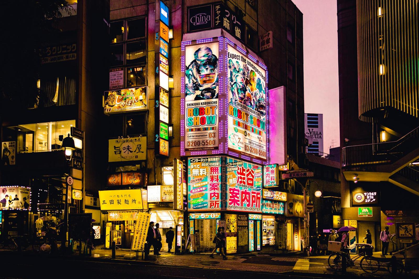 A neon-lit street corner with illuminated signage and pedestrians at dusk
