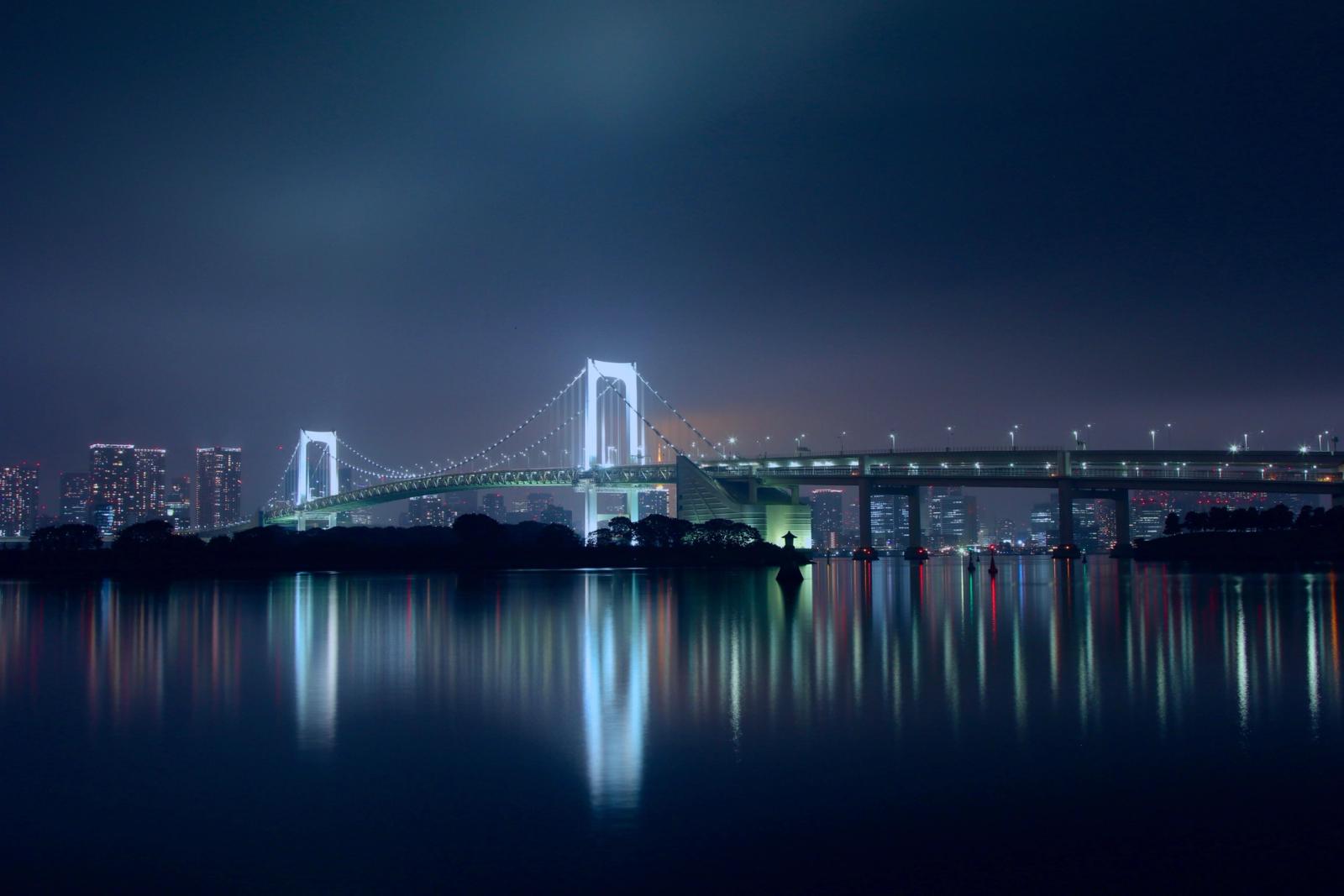 Capture of Rainbow Bridge in Tokyo, Japan at night, reflecting in calm waters