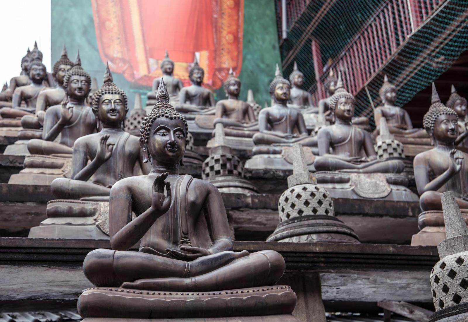 Rows of seated bronze buddha statues arranged in tiers at a temple