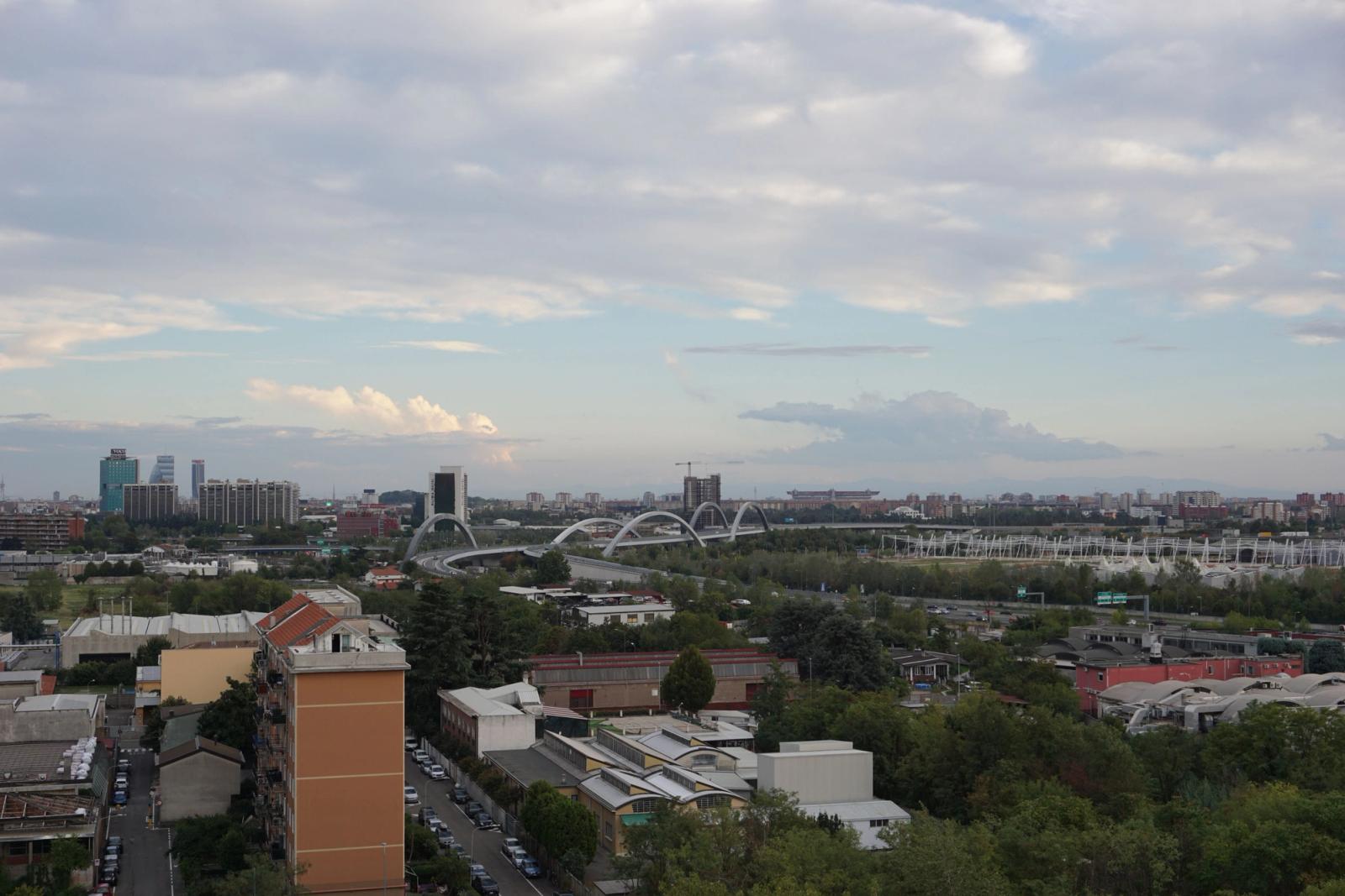 Explore the vibrant urban skyline of Milan with a view of modern architecture and lush greenery
