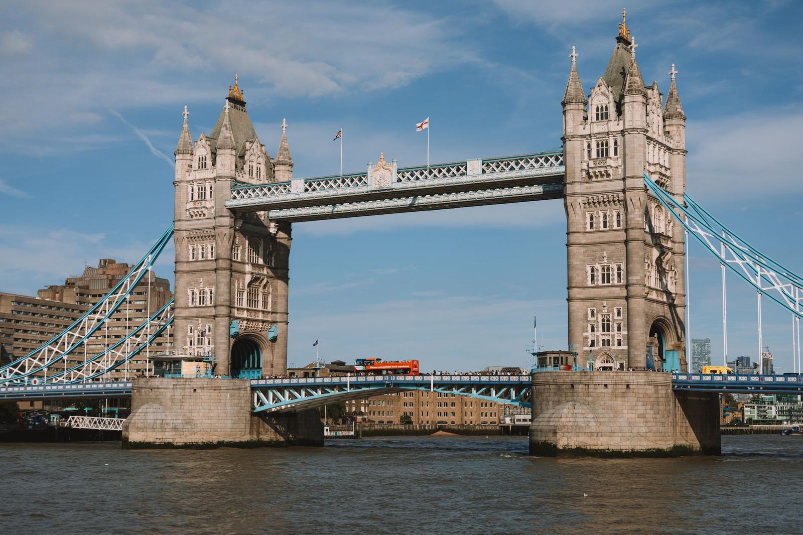 A twin-towered suspension bridge over a river against a clear blue sky
