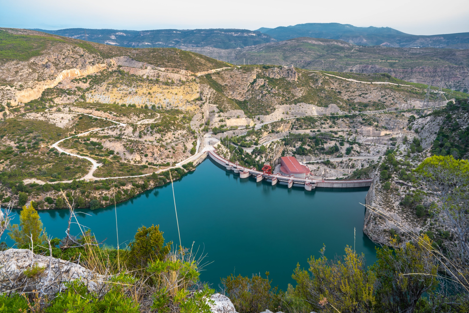 A breathtaking aerial view of the dam and turquoise reservoir in Cortes de Pallás, Valencia, Spain
