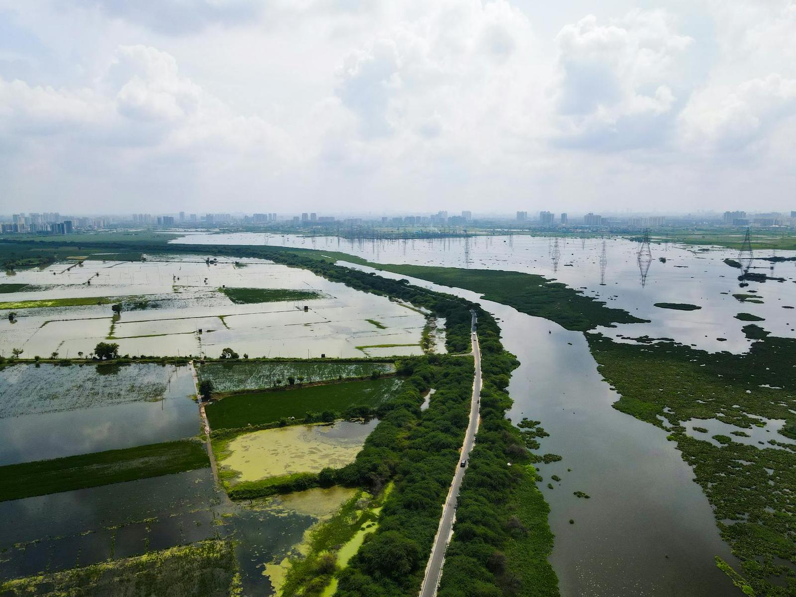 An aerial view of flooded fields and waterways near a distant city