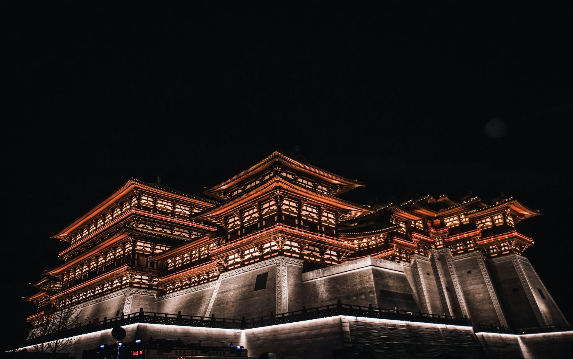 A multi-tiered pagoda temple illuminated in red and gold against a black night sky