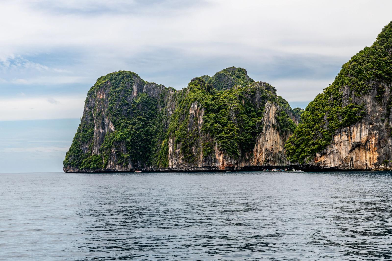 Beautiful cliffs covered in green foliage overlooking the calm sea in Phuket, Thailand