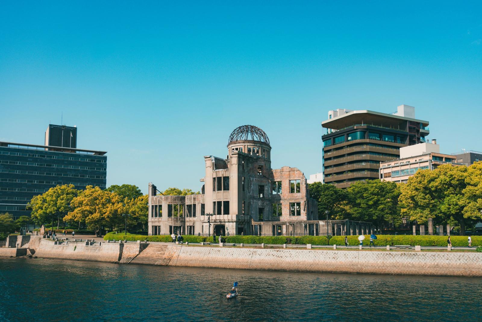 The Hiroshima Peace Memorial dome ruins beside a river with modern towers behind