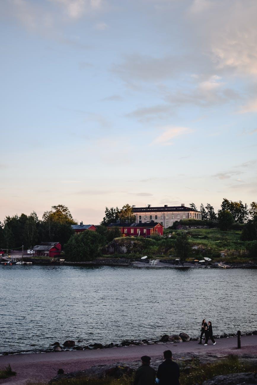 Waterfront building glowing at dusk with figures strolling the shore path