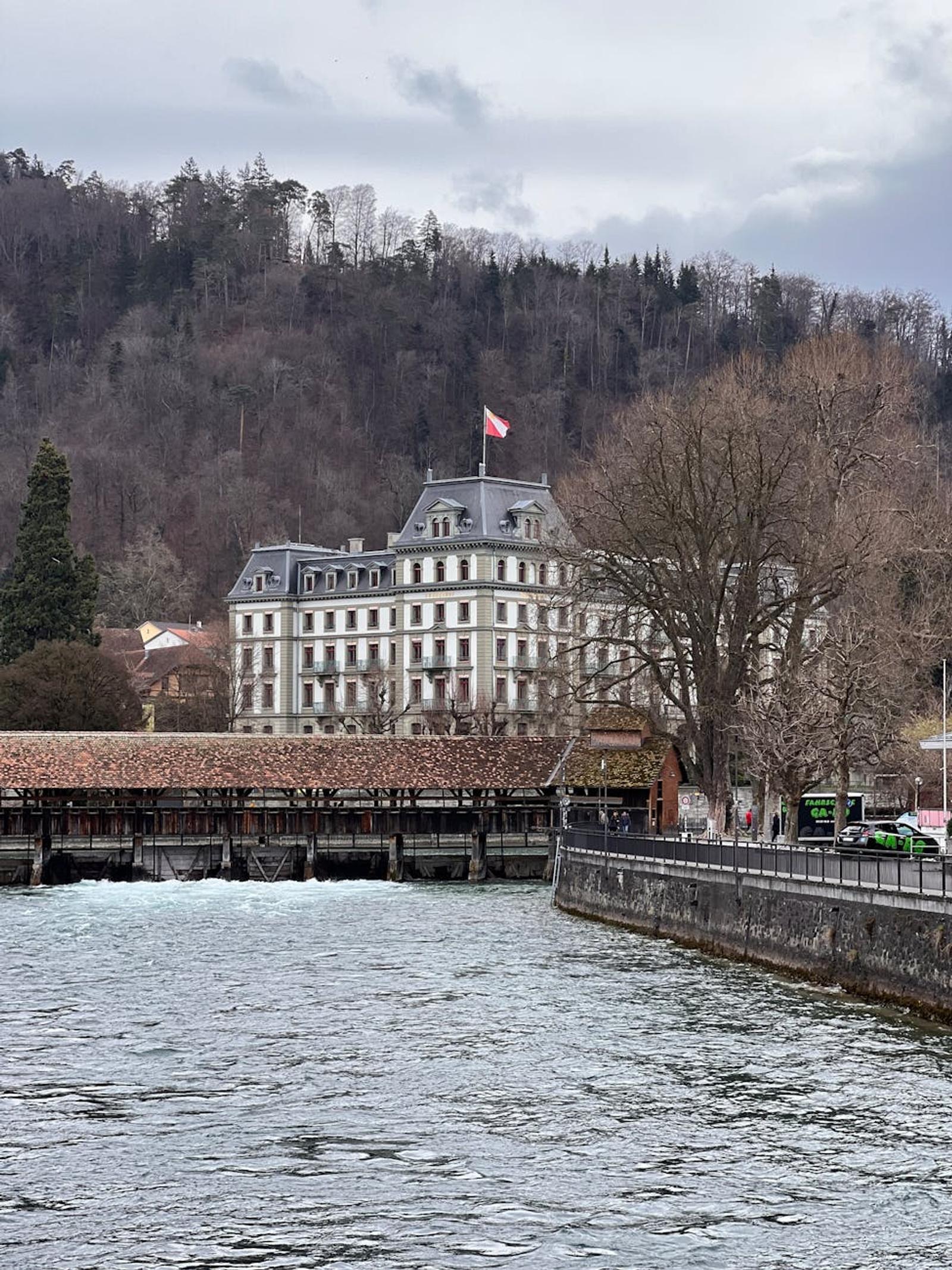 Charming view of a historic building by the river with Swiss flag, nestled in Thun, Switzerland
