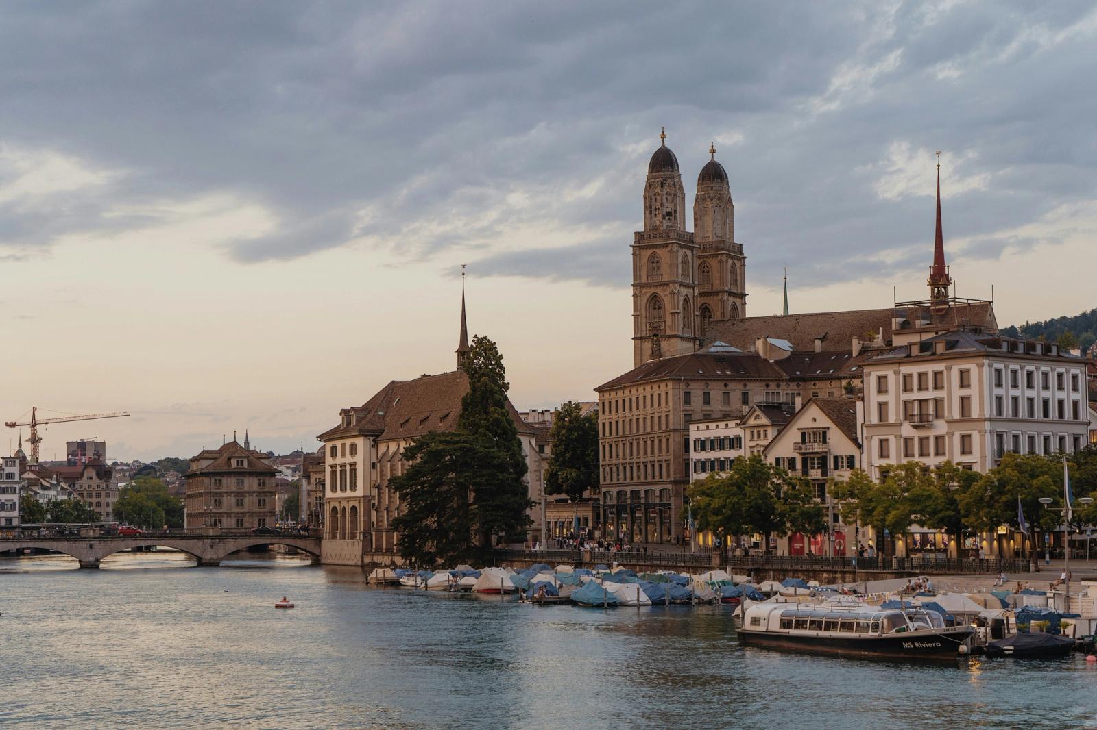 Scenic Zurich cityscape featuring the Grossmünster church along the Limmat River at dusk