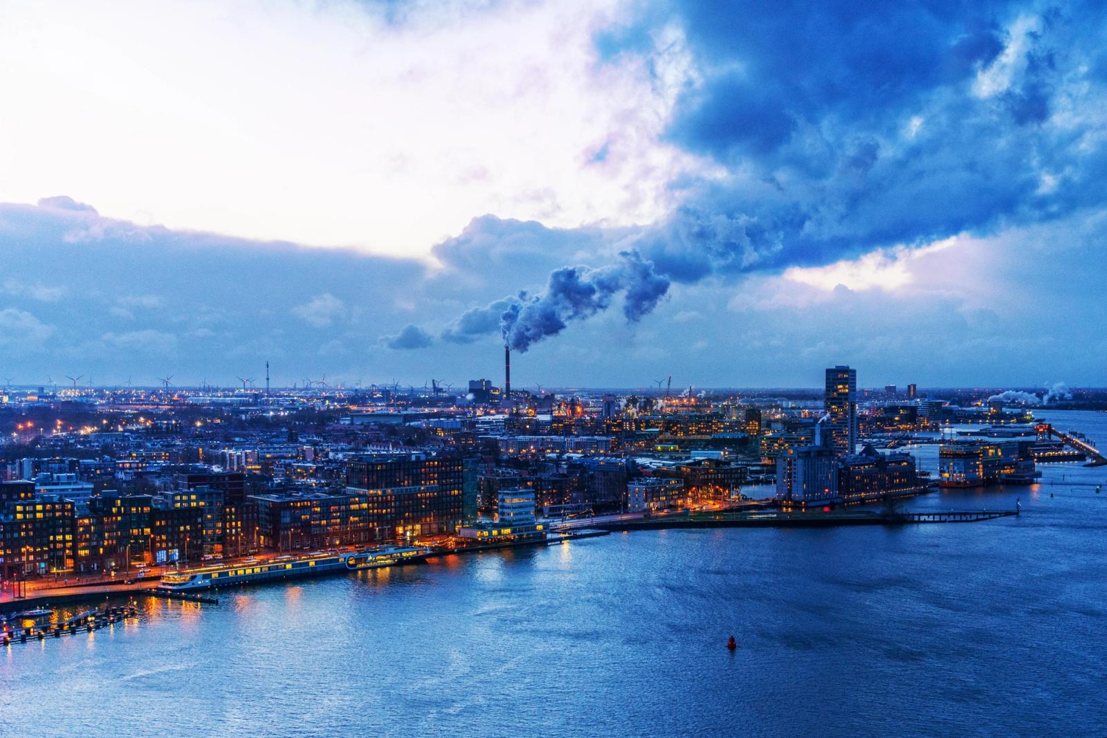 Stunning aerial view of city lights and a waterfront with a dramatic cloudy sky at dusk