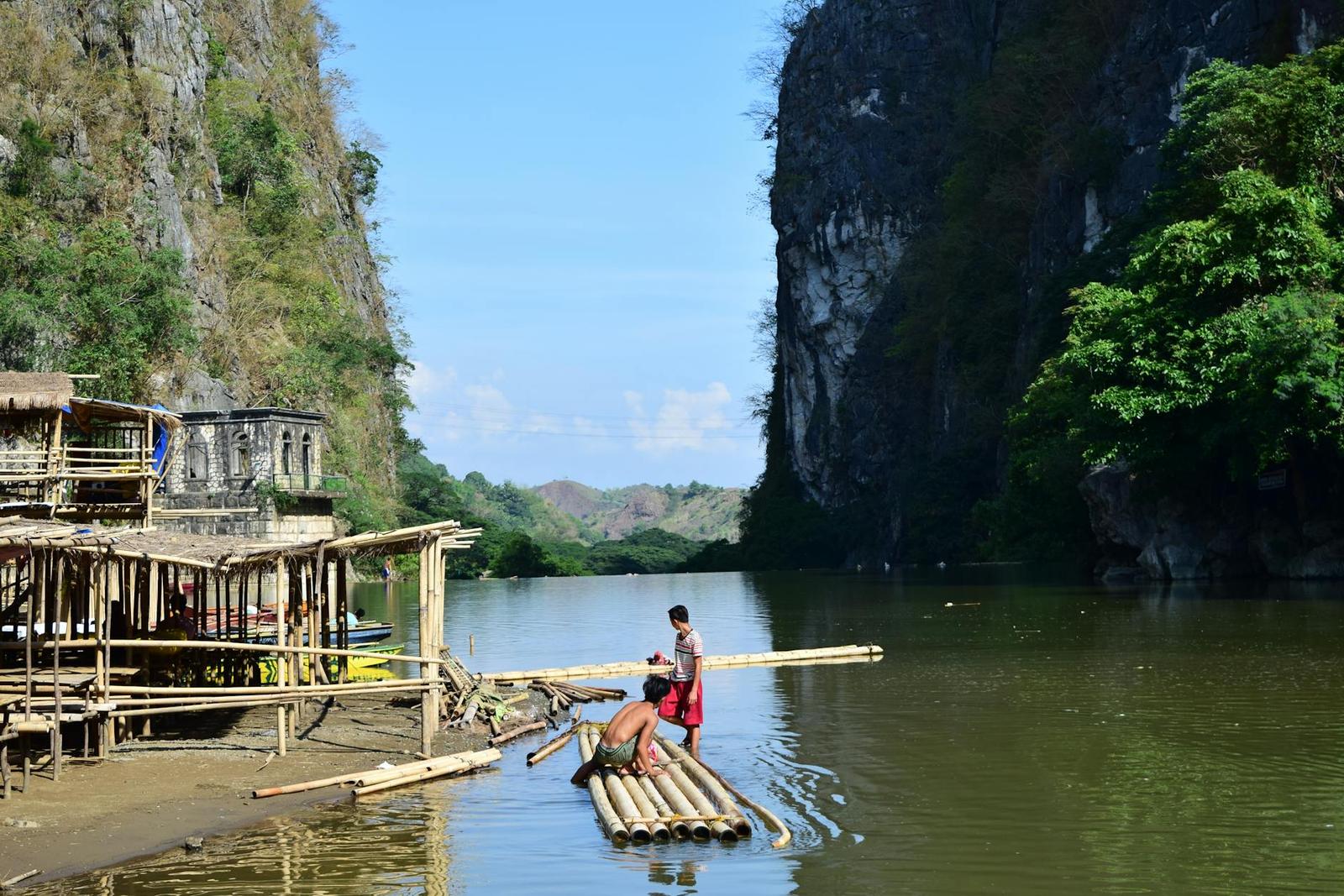 A bamboo raft poled between towering limestone cliffs on a river