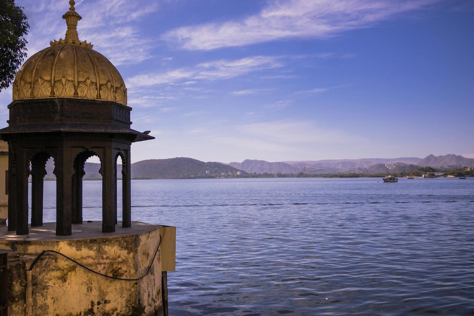 A golden-domed pavilion overlooking a wide lake and distant hills
