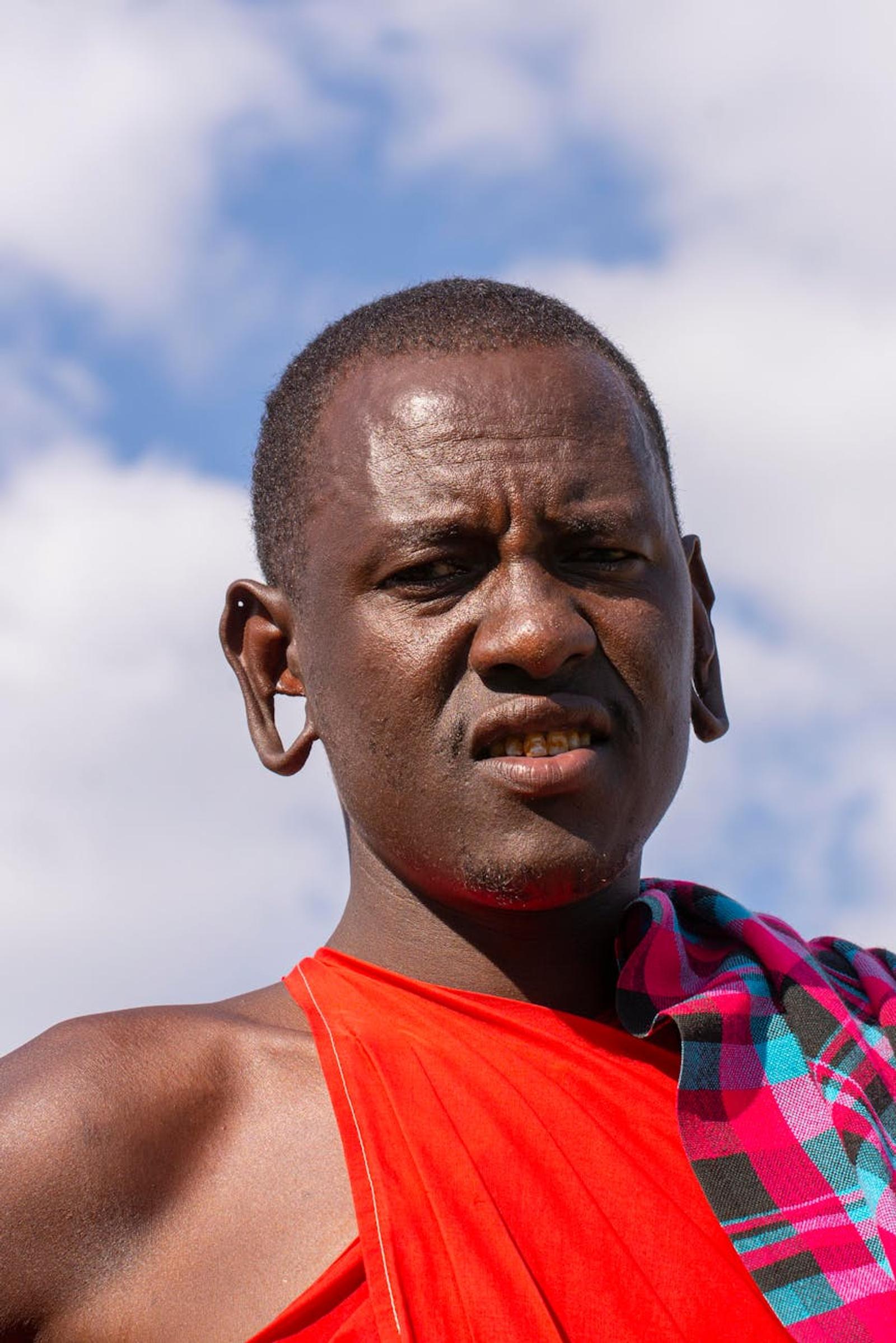 Close-up of a Maasai man in a red shawl against a cloudy sky